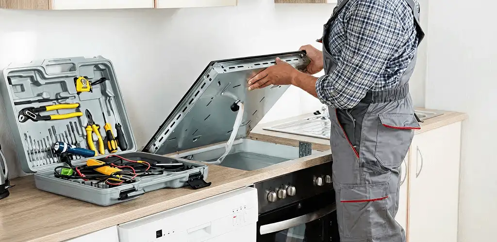 Handyman repairing a cooktop and checking wiring connections in Arvada, CO