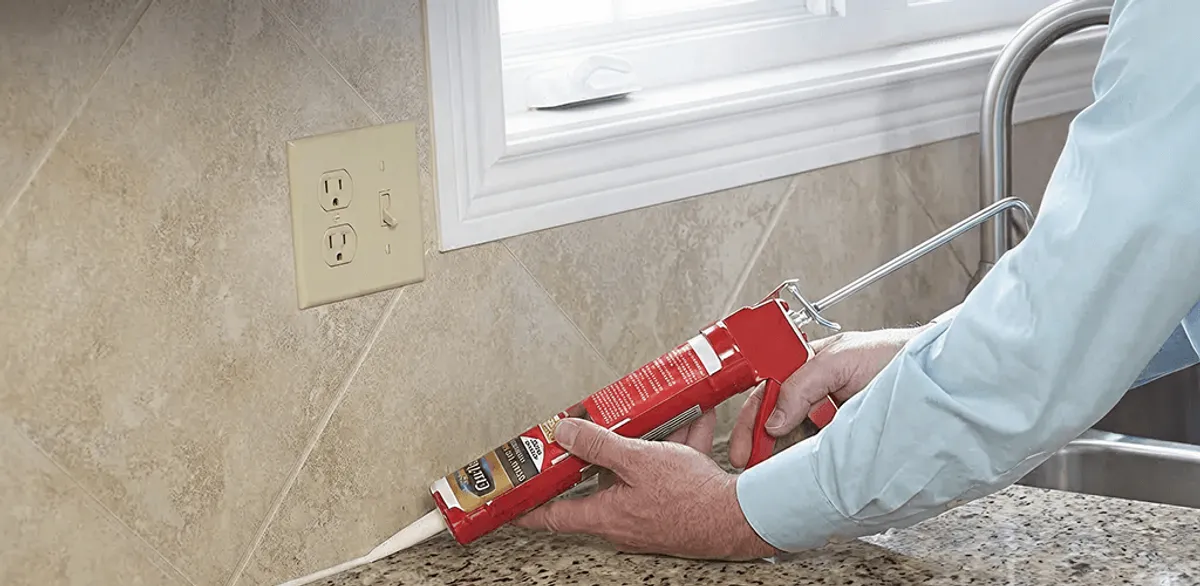 Handyman applying caulk along a kitchen backsplash and countertop seam in Arvada, CO