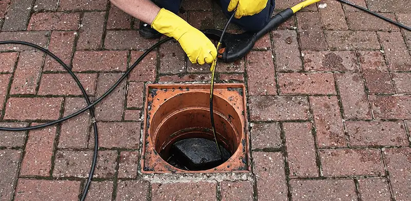 Drain cleaning technician using a drain snake to clear a clogged drain in Arvada, CO
