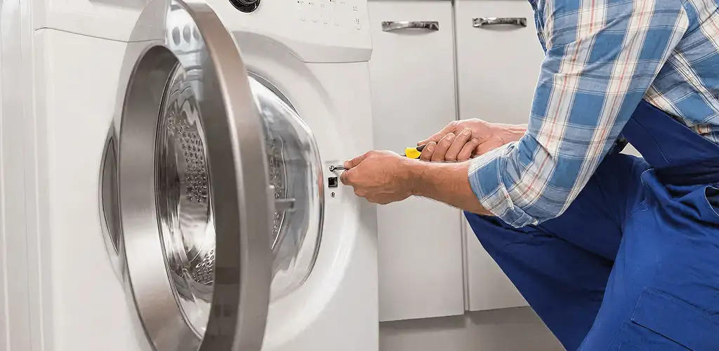 Handyman repairing a clothes dryer and checking electrical connections in Arvada, CO