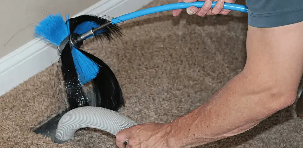 Dryer vent cleaning technician brushing lint from a vent line in Arvada, CO