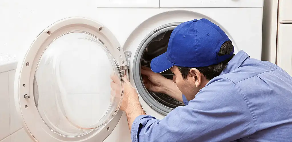 Washing machine repair handyman inspecting a front-load washer drum in Arvada, CO
