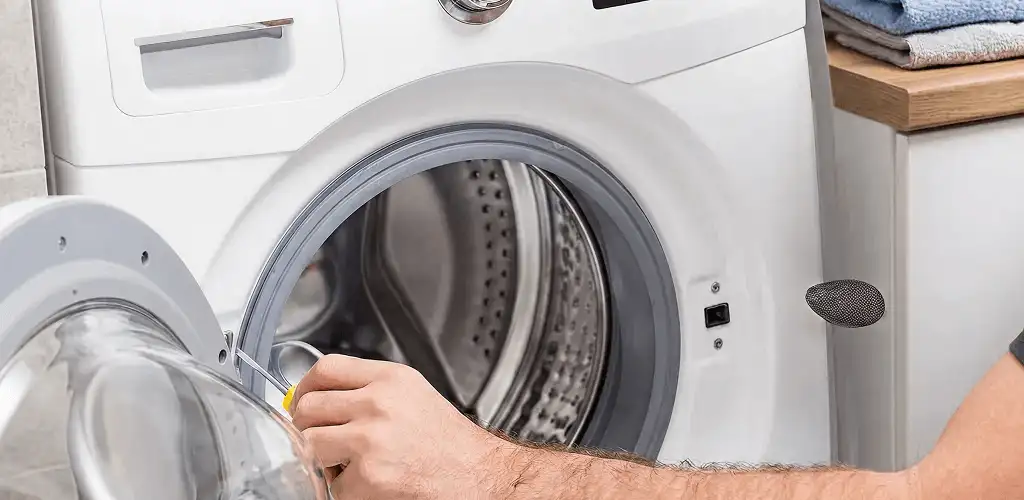 Handyman repairing a front-load washing machine and inspecting the drum in Arvada, CO