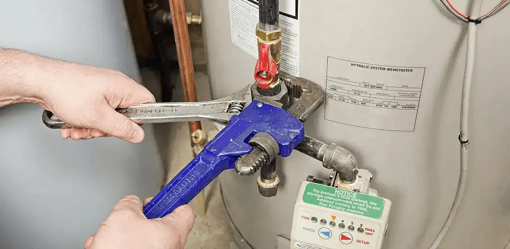 Water heater repair technician tightening the shutoff valve and supply line in Arvada, CO